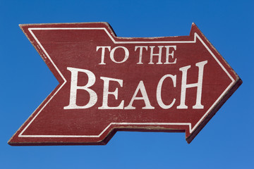 to the beach sign against the blue sky