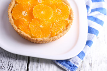 Fototapeta na wymiar Homemade orange tart on plate, on color wooden background