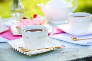 Coffee table with teacups and tasty cakes in garden