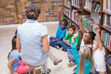 Cute pupils and teacher having class in library