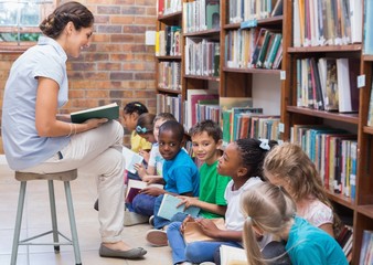 Cute pupils sitting on floor in library