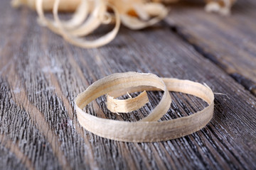 Wood shavings on grey wooden background closeup