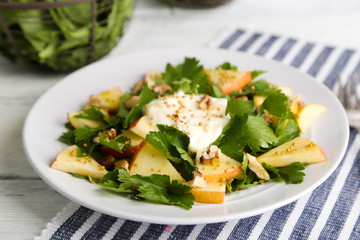 Green salad with apples, walnuts and cheese on wooden