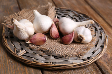 Fresh garlic on wicker mat, on wooden background