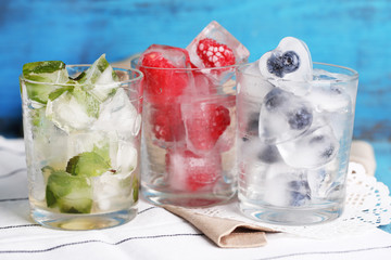 Ice cubes with mint leaves, raspberry and blueberry in glasses,