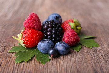 Ripe sweet different berries, on old wooden table