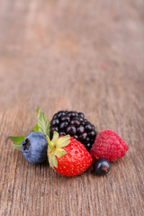 Ripe sweet different berries, on old wooden table