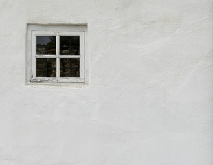 Obraz na płótnie Canvas The old white plastered wall with a small window