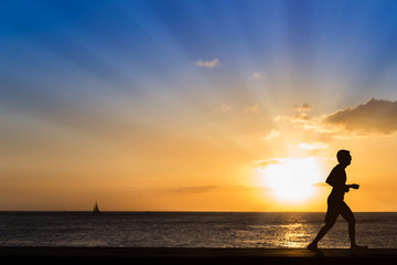 Obraz premium Silhouette of jogging man at the beach with sunset background