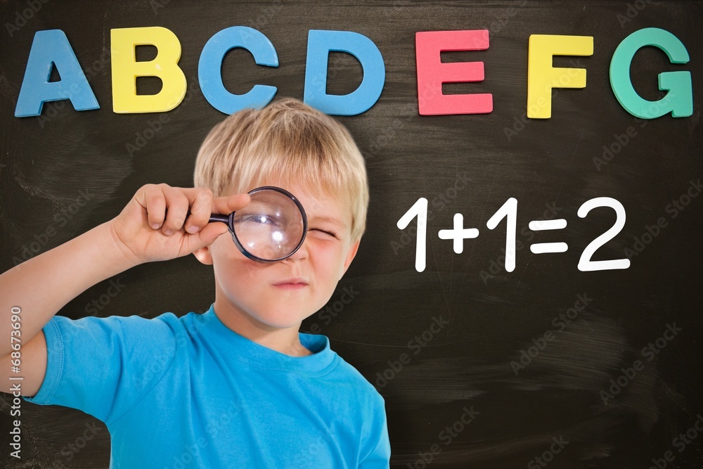 Poster composite image of cute boy looking through a magnifying glass