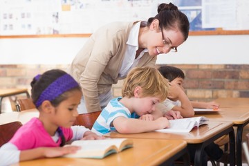 Obraz premium Pretty teacher helping pupil in classroom
