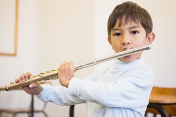 Cute pupil playing flute in classroom © WavebreakMediaMicro