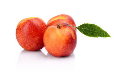 Three nectarines with leaf isolated on white