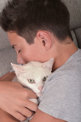 Boy with a white cat at home