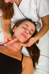 Attractive female patient receiving electro acupuncture on face