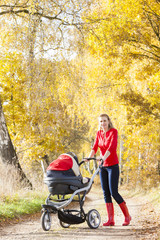 woman with a pram on walk in autumnal alley