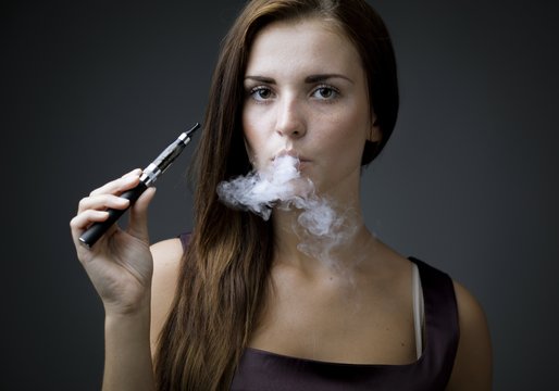 Elegant woman smoking e-cigarette with smoke