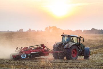 Tractor in sunrise plowing the field 