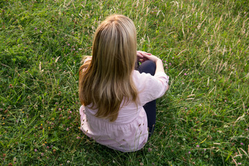 blonde frau sitzt im gras