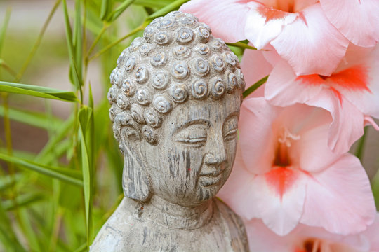 Boeddha in  bamboe tuin met bloemen