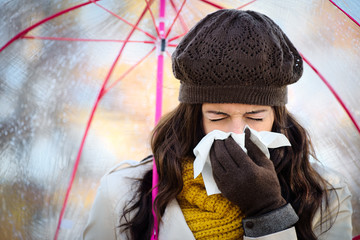 Woman coughing and blowing her nose in autumn