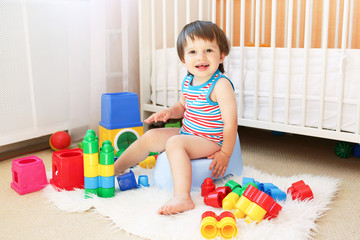 baby with toys sitting on potty