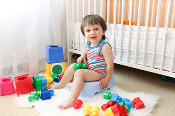 baby boy sitting on potty - obrazy, fototapety, plakaty