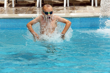 Fototapeta na wymiar Young boy jumping in the pool on vacation