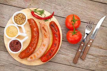 Various grilled sausages with condiments and tomatoes