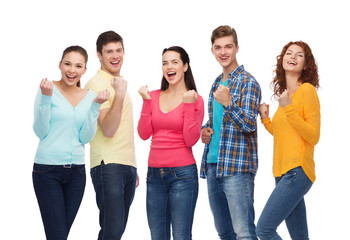 group of smiling teenagers showing triumph gesture