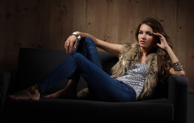 Obraz premium Portrait of elegant woman sitting on black sofa wearing a blue