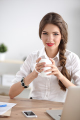 Young businesswoman sitting on the desk with cup in office