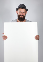 Portrait of young man in hat holding a blank, isolated on white