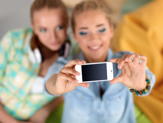 Two girls taking pictures on the phone at home