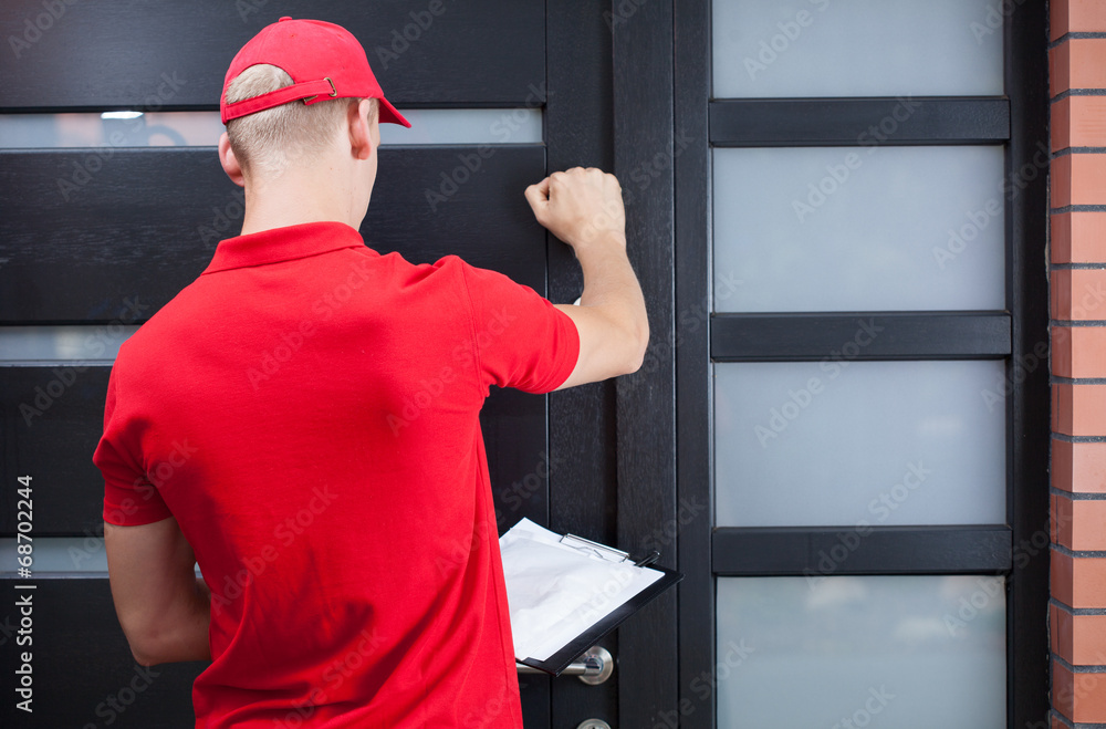 Wall mural delivery man knocking on the client's door