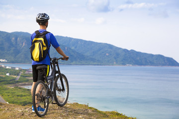 young man standing on the mountain with bike