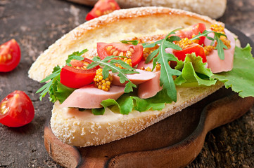 Sandwich with sausage, lettuce, tomato and arugula