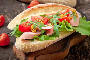 Sandwich with sausage, lettuce, tomato and arugula