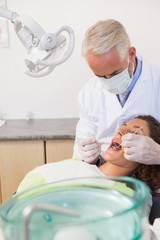 Obraz premium Dentist examining a patients teeth in the dentists chair