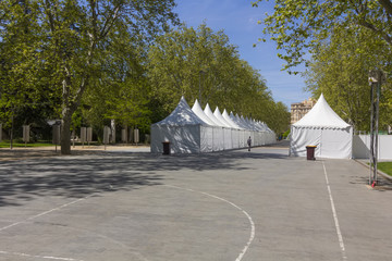 row of white tents on an empty Street among trees