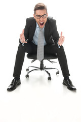 Young businessman shouting and sitting on a chair.
