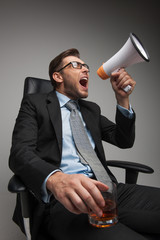 Young businessman shouting and sitting on chair.