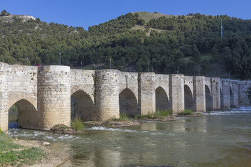 Fototapeta na wymiar Old stone bridge block with arches and water