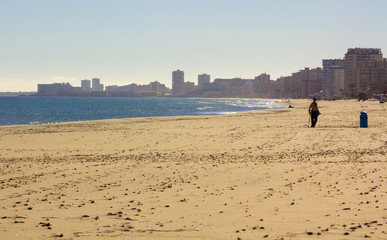 white sand beach with person searching with metal detector