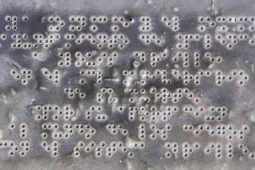 Braille letters on an old metal plate