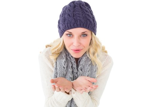 Pretty blonde in winter fashion blowing over hands