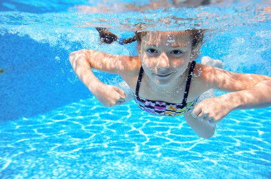 Happy active underwater child swims in pool and having fun