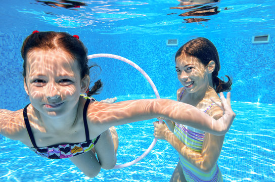 Happy active kids swim in pool and play underwater