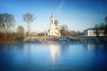 Fototapeta na wymiar Church on the banks of the frozen river ice winter