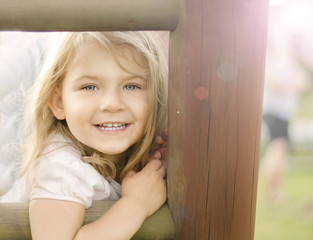 uśmiechnieta dziewczynka na tle drewnianego ogrodzenia - obrazy, fototapety, plakaty